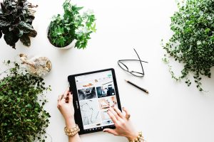 Person using black tablet computer with plants in the background