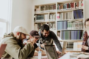 Group of people laughing and working on a laptop.